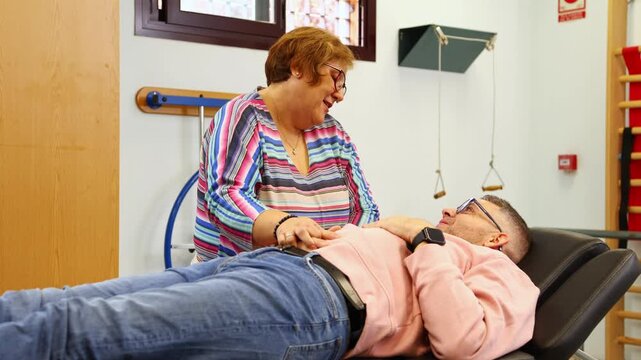Physical therapist examining patient's abdomen in clinic