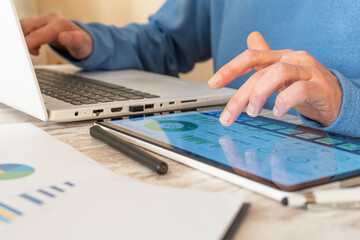 Hands using tablet showing esg charts while typing on a laptop, analyzing sustainability and financial metrics for corporate responsibility, carbon footprint and green business strategy