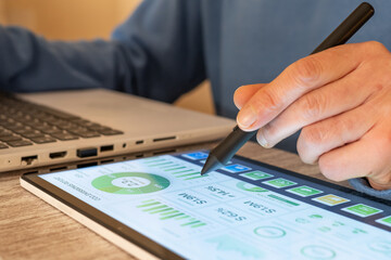 Business professional using a digital tablet and stylus to analyze carbon emissions data, financial growth, and environmental, social, and governance metrics for sustainable development