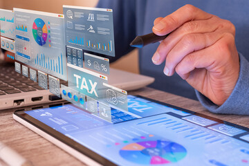 Hand using a stylus to navigate a tablet displaying a financial dashboard with a virtual tax window and various data visualizations, illustrating modern digital tax management and planning
