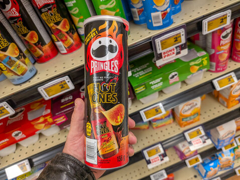 Canada, Quebec, 02 November 2025 : Hand holding spicy Pringles Hot Ones chips can in grocery store.