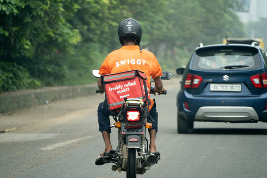 Food delivery rider from Swiggy with a zomato bag showing the multi hatting with food technology apps that the gig workers do to ensure sustainable income