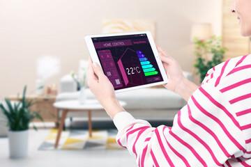 Smart home system. Woman using app on tablet computer to control house features in room, closeup