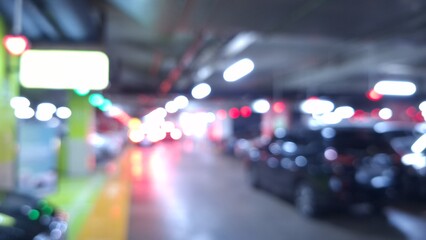Abstract blurred background of a busy underground parking garage with bright bokeh lights from car taillights and overhead fluorescent lamps. © Ahmad