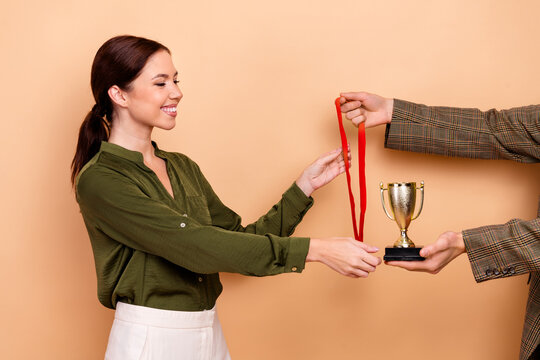 Young businesswoman receives award medal during office celebration with smiling focus on trophy