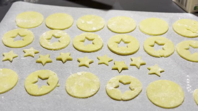 Homemade Alsatian bredele cookie dough cut into star and round shapes on parchment-lined baking tray, lightly floured and ready to bake for Christmas holiday treats
