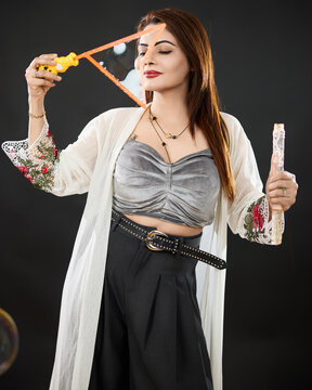 tudio portrait of an elegant woman calmly forming a soap bubble with a bubble wand while holding the solution bottle. Conceptual image expressing mindfulness, creativity, balance, calmness, 