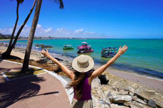 Young woman with open arms dreaming to explore with a raft the natural swimming pools of Ponta Verde, Maceio, Brazil
