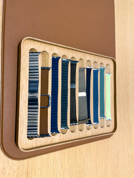 Germany Berlin December 25, 2025. Apple Watch bands displayed on a wooden tray inside an Apple Store. Different materials and colors showcase customization options.
