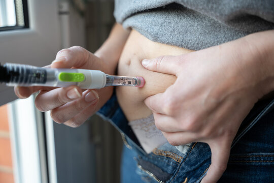 Adult administering insulin into the abdomen at home