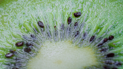Detailed cross-section of ripe kiwi fruit showing vibrant green flesh and water droplets. Abstract background of healthy vegetarian ingredient. Photo