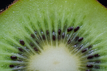 Detailed cross-section of a ripe kiwi fruit showing vibrant green flesh and wet seeds. Abstract background of healthy vegetarian ingredient. Photo