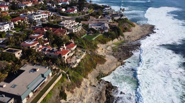 Drone View of Birds Flying over Coastal Tidal Waters Along Luxury Beachfront Real Estate. La Jolla Beach, San Diego.