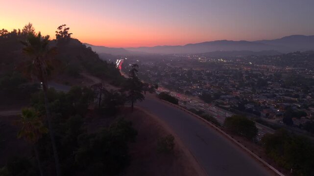 Cars driving on Highway in LA Traffic at Sunset, headed North towards San Fernando Valley. City skyline at sunset car driving along palm trees towards beautiful overlook viewpoint. Elysian Park
