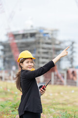 A female engineer overseeing an industrial plant project with heavy machinery as a backdrop demonstrates professional expertise, management skills, and business development capabilities.