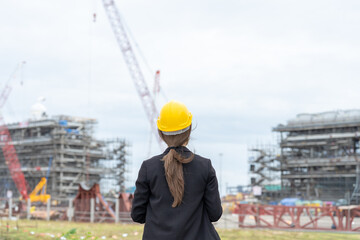 Professional female engineers working on industrial power plant construction sites coordinate to ensure business efficiency, safety standards, and the proper functioning of machinery.