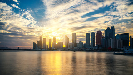 Obraz premium Sunset Over Modern City Skyline with Water Reflection