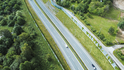 Fototapeta premium Trucks and Cars on Road by Green Barrier