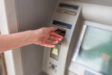 Plakat A person's hand inserting a credit card into an automated teller machine to perform a banking transaction.