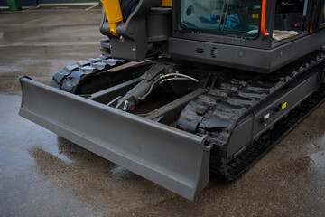Industrial excavator undercarriage with front blade and tracked drive system on paved surface, focused on construction machinery engineering and durability