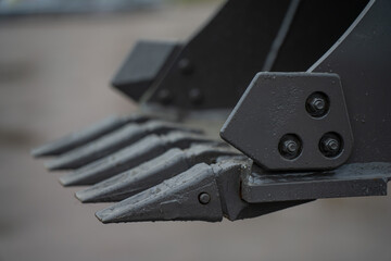 Construction excavator digging attachment featuring steel bucket teeth and connector plate, focused on earthmoving machinery engineering and durability