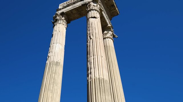 perspective tall corinthian columns topped intricately carved entablature stands boldly against deep cloudless blue sky rome upward empire dramatic 