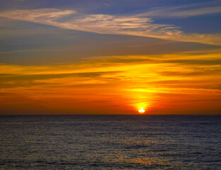 Fototapeta premium Puesta de sol anaranjada en el mar, en un entorno natural.