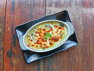 Baked spinach with cheese on a wooden table. Top view of Italian food
