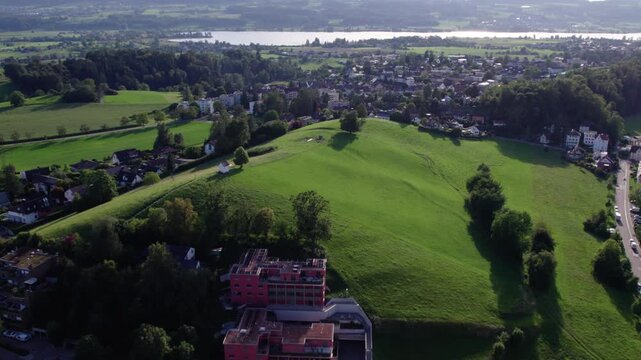 Aerial of a small city with a beautiful green hill and a lake, Uster, Switzerland