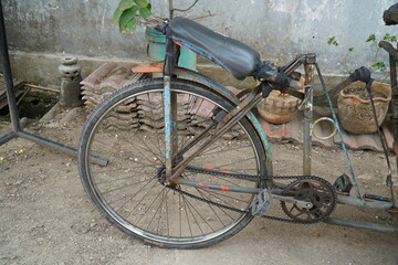 a rickshaw, a traditional Indonesian three-wheeled means of transportation, parked next to the house