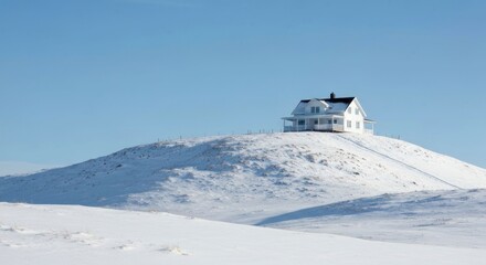 Solitary white farmhouse atop a snow-covered hill under a clear blue sky