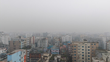 A densely populated urban cityscape with numerous buildings and a hazy atmosphere on a gloomy day