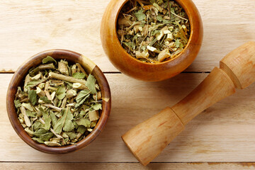 Lemon balm, Melissa officinalis, dried leaves in two wooden bowls with a pestle on a rustic wooden table