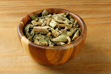 Lemon balm, Melissa officinalis, dried leaves in a wooden bowl on a rustic wooden table