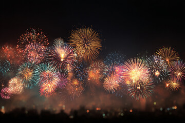 Brilliant fireworks explode in the night sky illuminating the darkness with bursts of vibrant color and light above a silhouetted cityscape