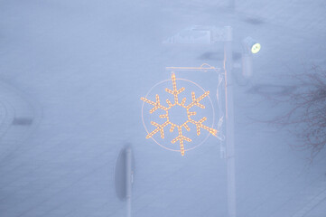 Weihnachtliche Beleuchtung in Form einer Schneeflocke an Laternenmast mit Spot im dichten Nebel in Neckartenzlingen, Ausblick vom neuen Rathaus.