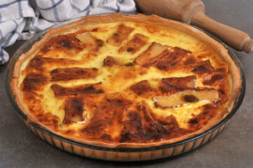 Tarte au camembert faite maison dans un plat en gros plan avec un rouleau &agrave; p&acirc;tisserie et un torchon au second plan