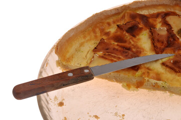 Vue partielle d'une tarte au camembert faite maison entam&eacute;e dans un plat avec un couteau en gros plan isol&eacute;e sur fond blanc