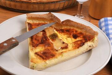 Part de tarte au camembert dans une assiette avec un couteau servie &agrave; table en gros plan