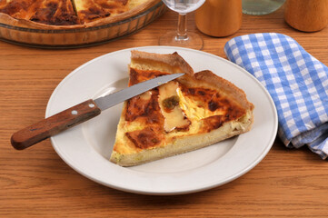 Part de tarte au camembert dans une assiette avec un couteau servie &agrave; table en gros plan