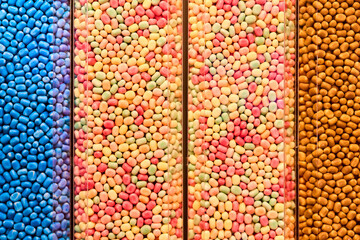 Colorful jelly bean candies in transparent containers arranged in vertical rows. Bright sweet background with vibrant textures, candy shop display, playful mood, and confectionery lifestyle concept.