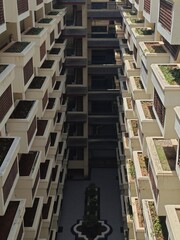 A high-angle, symmetrical perspective of a modern apartment building's inner courtyard, featuring clean white balconies with wooden privacy screens and planter boxes overlooking a tiled central ground
