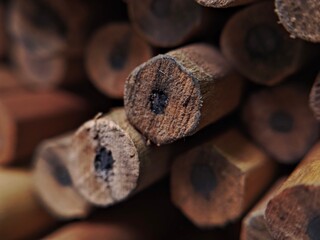 An extreme macro, shallow depth-of-field shot showing the weathered ends of a bundle of hexagonal wooden pencils with dark graphite leads.