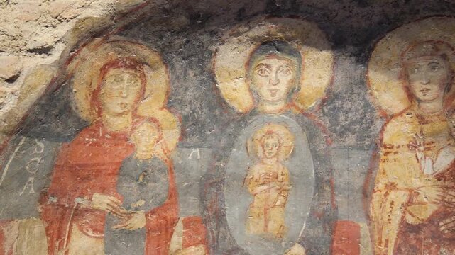 weathered fresco three haloed female figures holding child like faded reds golds grays ancient religious iconography rome italy childlike imagery gold tones gray hues 
