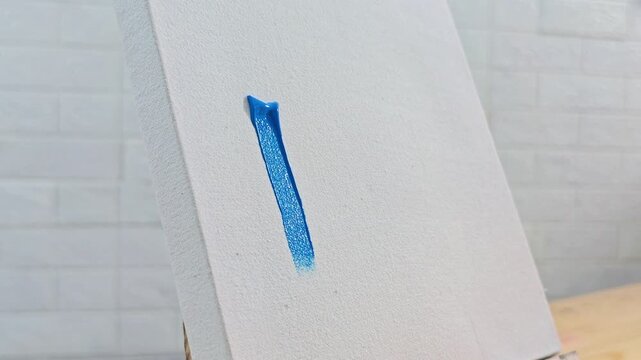 Person Painting Blue Brush Strokes on Canvas.