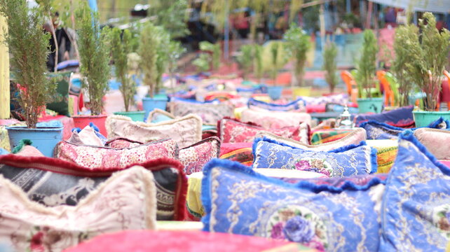 Colorful outdoor seating with traditional Berber rugs, potted trees & silver teapot at a rustic cafe in the scenic Ourika Valley near Marrakech, Morocco &mdash; perfect for travel, culture & lifestyle conte