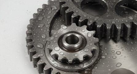 wet metallic gears with water droplets showcasing industrial mechanics and precision engineering on a white background.