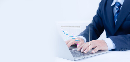 Businessman working on laptop with virtual data analytics dashboard, financial charts and project timeline overlay, representing digital strategy, business growth, fintech data analysis and technology