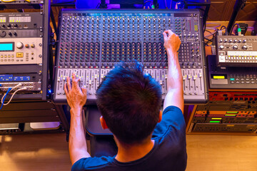 top view of asian music producer working in home recording studio, showing professional studio audio equipments. recording concept