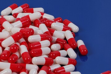 Close-up of a pile of red and white capsules lying on a blue background